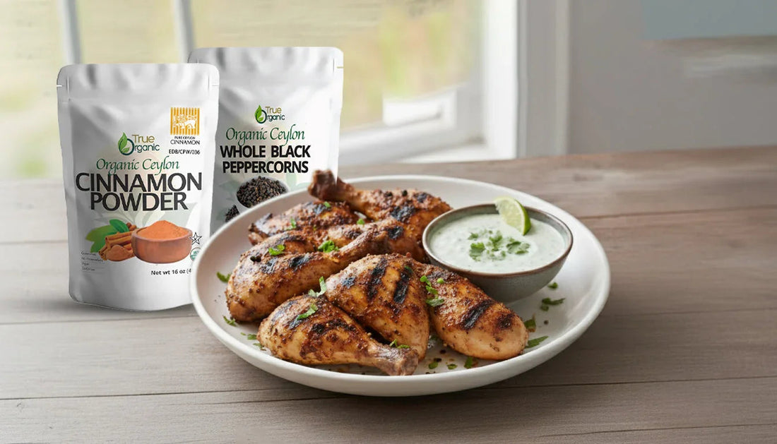 Grilled chicken drumsticks garnished with herbs on white plate with lime sauce and organic cinnamon powder and black peppercorns packets