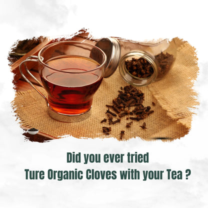 Glass cup of tea with spilled organic whole cloves from glass jars on burlap cloth